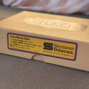 Kartonová krabice s nápisem ANTIQUITY GUITAR PICKUPS. Na boku je nalepený žlutý štítek s fialovým okrajem, který obsahuje text Texas Hot for Strat a…