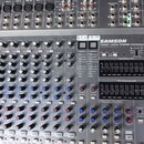 Stříbrný mixážní pult s nápisem SAMSON TXM20 1000W STEREO POWERED MIXER a označením 24 DSP DIGITAL EFFECTS. Zařízení obsahuje řady potenciometrů, pře…
