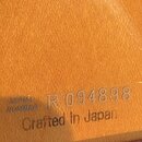 Detail dřevěného povrchu nástroje s nápisy. Je zde uveden text SERIAL NUMBER R 094898 a pod ním Crafted in Japan. Povrch je lakovaný a vykazuje drobn…