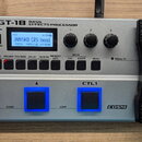 Stříbrný basový efektový procesor s černým pedálem. Na horní části je nápis BOSS GT-1B BASS EFFECTS PROCESSOR a displej s textem JAMISKO CRS bend, U1…