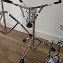 Chromovaný stojan na činely s třemi nohami a černými gumovými koncovkami. V horní části je mechanismus s třemi rameny zakončenými černými plastovými…