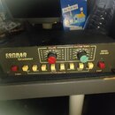 Černý elektronický rytmický doprovod s nápisem CONRAD ELECTRONIC Drummer. Na přední straně jsou dva otočné ovladače označené VOLUME a RHYTHM TEMPO, č…