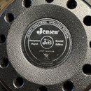 Záběr na zadní část černého reproduktoru s texturovaným povrchem a otvory v rámu. Uprostřed je kulatý štítek s nápisy JENSEN INDUSTRIES · SPEAKERS DI…