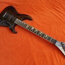 Tmavně hnědá elektrická kytara s tmavým hnedým povrchem a hmatníkem z dřeva. Na hlavě je zlatý nápis KRAMER. Nástroj má dva humbuckery, jeden tónový…