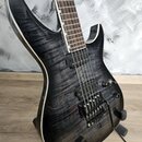Elektrická kytara s tmavě šedým, vrstveným povrchem imitujícím dřevo a bílým lemováním kolem korpusu. Nástroj má dva snímače typu humbucker, jeden ov…