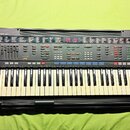Černý digitální klavír s bílými a černými klávesami. Na ovládacím panelu je vlevo nápis YAMAHA PSR-4500 a vpravo dole na šasi nápis DASSYSTEM. Nástro…