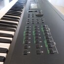 Černý digitální klavír s klasickou klaviaturou. Na ovládacím panelu jsou vidět řady tlačítek s nápisy OP 1 až OP 6, OPERATOR SELECT a ELEMENT ON/OFF.…