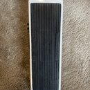 Bílý efekt pedál s černou žebrovanou gumovou plochou. Na gumové části jsou svisle vyrazeny nápisy INSTRUMENT a AMPLIFIER. Povrch bílého rámu vykazuje…