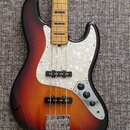 Elektrická basová kytara s trupem v barevném přechodu od černé přes červenou k žluté. Nástroj má bílý perleťový pickguard a hmatník z jasného dřeva s…