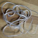 Průhledný, pletený kabel s několika konektory. Kabel je v rozmotané poloze na dřevěném povrchu. Na kabelu nejsou žádné viditelné značky ani nápisy.