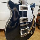 Tělo elektrické kytary v tmavě modré barvě s bílým lemováním. Na stříbrném plechu je svisle napsáno GRETSCH. Nástroj má dva snímače, stříbrný most a…
