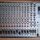 Stříbrošedý mixovací pult s nápisy BEHRINGER, EURORACK MX 2642A a 26 INPUTS MIXING CONSOLE. Zařízení obsahuje řadu vertikálních kanálů s knoflíky, po…