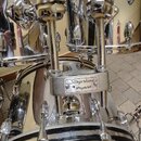 Detailní pohled na chromovanou bicí sadu s dvěma tomami namontovanými na basovém bubnu. Na držáku je viditelný nápis Slingerland is percussion a na s…