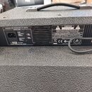 Záběr na zadní panel černého hudebního komba s texturovaným povrchem. Na levém černém štítku jsou nápisy DESIGNED AND ENGINEERED BY HARTKE, HARTKE.CO…
