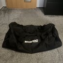Černá transportní taška z textiledního materiálu s několika úchopy. Na přední straně je bílý nápis ROCKBAG a pod ním menší text by Warwick. Taška vyk…