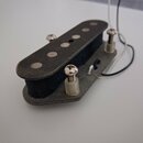 Černý humbucker s kovovým krytem a šesti viditelnými póly. Snímač je upevněn na plastové základně a jsou z něj vyvedeny bílý a černý vodič. Povrch kr…