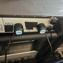 Detail zadní strany elektronického zařízení s konektory. Jsou zde viditelné nápisy REMOTE POWER IN, MIDI a PEDAL. Do zařízení jsou zapojeny dva černé…