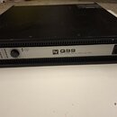 Černý výkonový zesilovač s kovovým šasi. Na předním panelu je nápis „EV Q99 PROFESSIONAL POWER AMPLIFIER“, kontrolky PROTECT a POWER, dva ovratidla p…