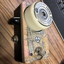 Kytarový efekt s obalem z lakovaného dřeva a barevnými grafickými prvky. Na horní části je bílé otočné kolečko s nápisem BY SALVATION AUDIO TONE WHEE…