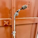 Kovový stojan s ramenem a připevněným mikrofonem v černé barvě. Na hlavici mikrofonu je nasazen tmavě šedý pěnový popovlak. Na kovové části ramene je…