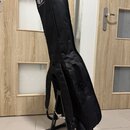 Černý poloměký pouzdro (gig bag) na hudební nástroj, umístěné na černém stojanu. V horní části pouzdra je bílé logo a nápis "PRO MUSIC GEAR". Stojan…