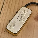 Zlatý kytarový snímač obdélníkového tvaru s kovovým krytem. Na povrchu je vyražen nápis Forte a grafický symbol připomínající rozptylování zvukových…