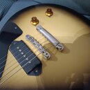 Detail elektrické kytary s žlutým gradientním lakem a černým pickguardem. Na těle je vidět jeden černý humbucker, stříbrný kobylník a dvě zlaté ovlád…