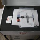 Otevřená bílá krabice s černou vložkou, ve které se nachází dokumentace a příslušenství. Na bílém papíře je vidět nápis Product Catalog a označení mo…