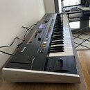 Černý digitální klavír s bílým spodním rámem. Na levé straně je bílý nápis Roland. V horní části panelu jsou umístěny ovládací prvky, displej a nápis…