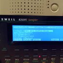 Detailní pohled na ovládací panel sampleru značky KURZWEIL, model K2500RS Sampler. V centru je modrý LCD displej s textem „EffectsMode“, „XPose:36ST“…