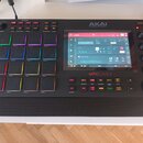 Černý samplovač MPC LIVE II značky AKAI PROFESSIONAL. Zařízení má 16 podsvícených padů, ovládací knoflíky a centrální displej s rozhraním softwaru. N…