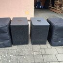 Čtyři černé reproduktory umístěné vedle sebe na dlažbě. Dva prostřední jsou v pevných skříních s kovovou mřížkou, dva krajní jsou zakryty černými tex…