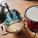 Sada tří bubnů v modré a červené barvě s kovovým kováním. Na blanách dvou bubnů je vidět nápis EVANS. Střední modrý buben má na blaně logo Sonor a je…