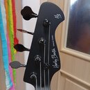 Černá hlava basové kytary s четыřmi ladicími kolíky. Na povrchu je bílý nápis „Harley Benton Deluxe Series“ a v horní části logo „HB“. Povrch je hlad…