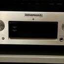 Stříbrný síťový audio přehrávač s kovovým povrchem a dvěma cylindrickými nožkami. Na předním panelu je nápis marantz a pod ním text NETWORK AUDIO PLA…