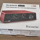 Fotografie znázorňuje krabici od USB audio rozhraní v červené barvě. Na obalu je uveden název Scarlett Solo a popis THIRD-GENERATION 2-IN, 2-OUT USB…