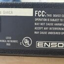 Fotografie zachycuje zadní štítku černého elektronického zařízení. Na bílém poli jsou uvedeny údaje: 19920007601 - 64 Voice Expandable Synth, MODEL:…