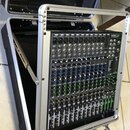 Míchací pult umístěný v hliníkovém transportním kufru. Na horním pravém rohu přístroje je viditelné logo Proel a nápis "PROMIX". Povrch pultu je čern…