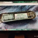 Fotografie zachicuje elektronickou součástku v kovovém, oválném šasi. Na bílé nálepce je uveden text EMG-SLV, MADE IN USA, 1710.01, (21)4870185, 07/0…