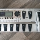 Stříbrný kytarový efektový procesor s nápisem BOSS GT-10 GUITAR EFFECTS PROCESSOR. Zařízení má digitální displej, několik ovládacích tlačítek a v pra…