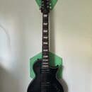 Černá elektrická kytara s dvojsečným stupňovitým hmatníkem a dvěma humbuckery. Na hlavě je bílé logo Ltd. Nástroj je umístěn před dvěma zelenými hexa…