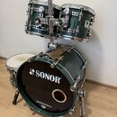 Sada bubnů v tmavě zelené barvě s chromovaným kováním. Na černém předním bendle basového bubnu je bílé logo SONOR a nápis DRUMCENTER.CZ. Na jednom z…