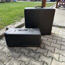 Dvě černé reproduktorové skříně s povrchem z imitace kůže. Obě mají na horní straně černé úchytky a na přední straně reliéfní vzor ve tvaru kříže. Na…