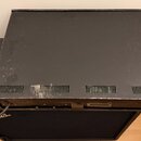 Černý rackový přístroj s kovovým šasi a ventilačními mřížkami na zadní straně. Na zadním panelu jsou viditelné konektory a nápis SHOCK HAZARD: DO NOT…