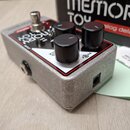 Stříbrný efektový pedál s kovovým šasi a černými ovládacími knoflíky. Na horní straně je nápis MEMORY TOY a analog delay, dále jsou vidět označení IN…