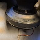Fotografie zachycuje zadní část reproduktorového jednotky umístěnou v bílé tlumicí vatové výplni. Viditelný je kovový magnet s černým plastovým kryte…