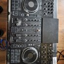 Černý DJ kontrolér s dvěma jog-koly a centrálním mixážním sekcí. Na přístroji jsou vidět nápisy DENON DJ a PRIME 4. Povrch v levé části mixážní sekce…