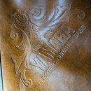 Detail hnědého koženého nebo syntetického materiálu s vyraženým ornamentem. V doprostředu je vyražen nápis YAMAHA a nad ním text SINCE 1887, pod ním…