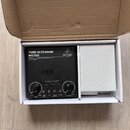 Černý předzesilovač v kartonové krabici. Na přístroji jsou nápisy TUBE ULTRAGAIN MIC300, VACUUM TUBE PREAMPLIFIER, AMPLYFIED WITH LIMITER a logo behr…