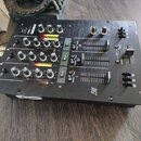 Černý mixážní pult s několika ovládacími knoflíky, posuvníky a LED indikátory úrovně. Na horní části je nápis "MIX-PRO" a pod ním "EFX 100 FX". Na bo…
